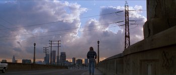 Movie still from “They Live” (1988), directed by John Carpenter – A person standing on a bridge with a city in the background; Extreme Wide shot, Low angle