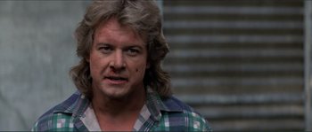 Movie still from “They Live” (1988), directed by John Carpenter – A person wearing a plaid shirt; Close Up shot, Over the shoulder angle