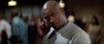 Movie still from “They Live” (1988), directed by John Carpenter – A man with a beard is holding a cell phone to his ear; Close Up shot, Low angle