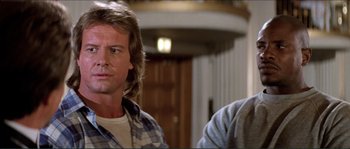 Movie still from “They Live” (1988), directed by John Carpenter – A man in a plaid shirt is looking at a man in a plaid shirt; Close Up shot, Low angle