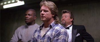 Movie still from “They Live” (1988), directed by John Carpenter – A group of men standing next to each other in a room; Medium shot, Low angle