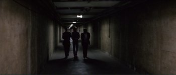 Movie still from “They Live” (1988), directed by John Carpenter – A group of people walking down a dark hallway; Wide shot, Low angle