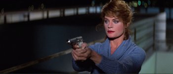 Movie still from “They Live” (1988), directed by John Carpenter – A woman is holding a gun in her hand; Close Up shot, High angle