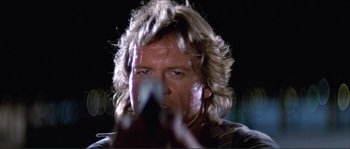 Movie still from “They Live” (1988), directed by John Carpenter – A person with long blonde hair; Close Up shot, Low angle