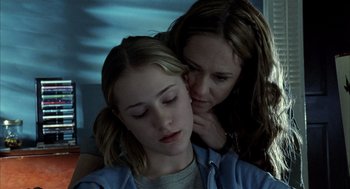 A woman whispers into the ear of a young girl