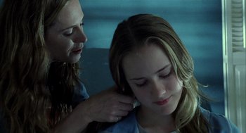 A young girl getting her hair combed by an adult