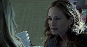 Movie still from “Thirteen” (2003), directed by Catherine Hardwicke – A woman sitting on the floor reading a book; Close Up shot, Over the shoulder angle