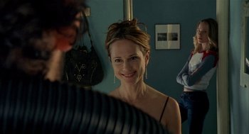 Movie still from “Thirteen” (2003), directed by Catherine Hardwicke – A woman smiling in front of a mirror; Medium shot, Over the shoulder angle