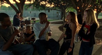 Movie still from “Thirteen” (2003), directed by Catherine Hardwicke – A man and a woman sitting next to each other on a park bench; Medium shot, Over the shoulder angle