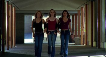 Movie still from “Thirteen” (2003), directed by Catherine Hardwicke – Three young women walking down a sidewalk in jeans and red shirts; Medium shot, Low angle
