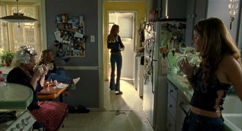 Movie still from “Thirteen” (2003), directed by Catherine Hardwicke – A woman standing in a kitchen looking into a doorway; Wide shot, Over the shoulder angle