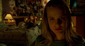 Movie still from “Thirteen” (2003), directed by Catherine Hardwicke – A young girl stares into the camera while a young boy sleeps in the background; Close Up shot, Over the shoulder angle