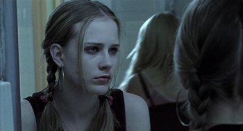 Movie still from “Thirteen” (2003), directed by Catherine Hardwicke – A woman with long blonde hair sitting in a dark room; Close Up shot, Over the shoulder angle