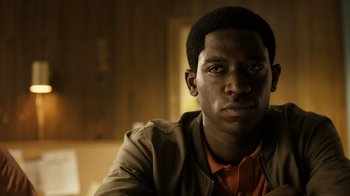 Movie still from “Snowfall” (2017), directed by Hiro Murai – A man with a brown jacket and orange shirt; Close Up shot, Low angle