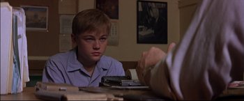 Movie still from “This Boy's Life” (1993), directed by Michael Caton-Jones – A young man sitting at a table with a cell phone in front of him; Close Up shot, Over the shoulder angle