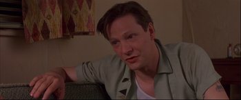 Movie still from “This Boy's Life” (1993), directed by Michael Caton-Jones – A person sitting on a couch in a living room; Close Up shot, Low angle