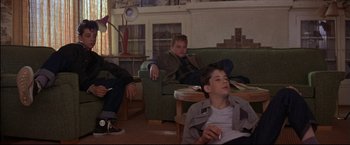 Movie still from “This Boy's Life” (1993), directed by Michael Caton-Jones – A group of young men sitting on a couch in a living room; Wide shot, Low angle