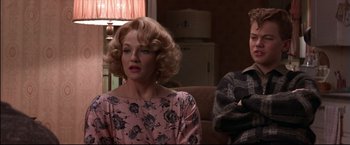 Movie still from “This Boy's Life” (1993), directed by Michael Caton-Jones – A woman with blonde hair sitting in a living room; Medium shot, Over the shoulder angle