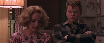 Movie still from “This Boy's Life” (1993), directed by Michael Caton-Jones – A man and a woman sitting next to each other on a couch; Medium shot, Over the shoulder angle