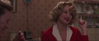 Movie still from “This Boy's Life” (1993), directed by Michael Caton-Jones – A woman with blonde hair and a red jacket smiling for the camera; Close Up shot, Over the shoulder angle