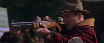 Movie still from “This Boy's Life” (1993), directed by Michael Caton-Jones – A man holding a rifle while wearing a cowboy hat; Close Up shot, Low angle