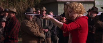 Movie still from “This Boy's Life” (1993), directed by Michael Caton-Jones – A woman is holding two guns in her hands; Medium shot, Over the shoulder angle
