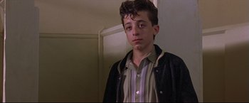 Movie still from “This Boy's Life” (1993), directed by Michael Caton-Jones – A young man standing in front of a wall; Medium shot, Low angle