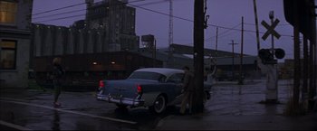 Movie still from “This Boy's Life” (1993), directed by Michael Caton-Jones – A man standing next to an old car on the side of the road; Wide shot, Low angle