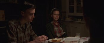 Movie still from “This Boy's Life” (1993), directed by Michael Caton-Jones – A man and a woman sitting at a table with a sandwich; Medium shot, Over the shoulder angle