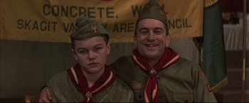 Movie still from “This Boy's Life” (1993), directed by Michael Caton-Jones – A man and a boy in scout uniforms posing for a picture; Medium shot, Low angle