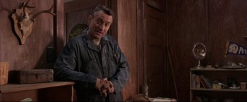 Movie still from “This Boy's Life” (1993), directed by Michael Caton-Jones – An older man standing in front of a wooden door; Medium shot, Low angle