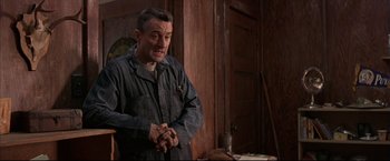 Movie still from “This Boy's Life” (1993), directed by Michael Caton-Jones – A man standing in front of a wooden wall; Medium shot, Low angle