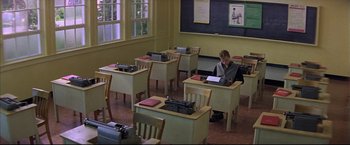 Movie still from “This Boy's Life” (1993), directed by Michael Caton-Jones – A man sitting at a desk in a classroom; Wide shot, High angle