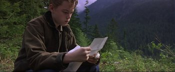 Movie still from “This Boy's Life” (1993), directed by Michael Caton-Jones – A young man sitting on the ground looking at a piece of paper; Close Up shot, High angle