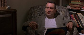 Movie still from “This Boy's Life” (1993), directed by Michael Caton-Jones – A man sitting in a chair holding a glass of beer; Medium shot, Low angle