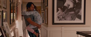 Movie still from “This Is 40” (2012), directed by Judd Apatow – A man holding a child in his arms in front of a wall; Medium shot, Over the shoulder angle