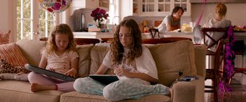 Movie still from “This Is 40” (2012), directed by Judd Apatow – A woman sitting on top of a couch with a laptop; Medium shot, Over the shoulder angle