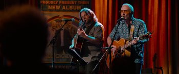 Movie still from “This Is 40” (2012), directed by Judd Apatow – A group of men playing a song on a stage; Medium shot, Over the shoulder angle