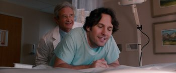 Movie still from “This Is 40” (2012), directed by Judd Apatow – A man in a hospital bed with a doctor behind him; Medium shot, Over the shoulder angle