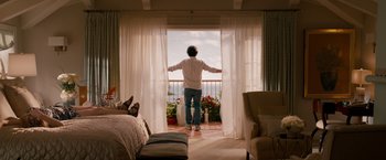 Movie still from “This Is 40” (2012), directed by Judd Apatow – A man standing in front of a window looking out at the sky; Wide shot, Low angle