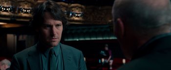 Movie still from “This Is 40” (2012), directed by Judd Apatow – A man wearing a suit and tie talking to another man in a theater; Close Up shot, Over the shoulder angle