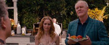 Movie still from “This Is 40” (2012), directed by Judd Apatow – A woman and a man standing next to each other holding plates of food; Medium shot, Over the shoulder angle