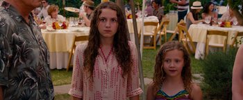 Movie still from “This Is 40” (2012), directed by Judd Apatow – Two young girls standing next to each other in front of tables; Medium shot, High angle