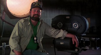 Movie still from “This Is Spinal Tap” (1984), directed by Rob Reiner – A man with a beard wearing a hat and a camera; Close Up shot, Low angle