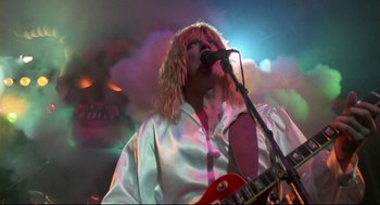Movie still from “This Is Spinal Tap” (1984), directed by Rob Reiner – A person with a microphone on a stage; Medium shot, Low angle