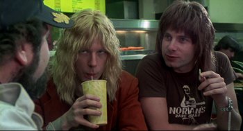 Movie still from “This Is Spinal Tap” (1984), directed by Rob Reiner – Two men sitting at a table drinking a drink; Close Up shot, Low angle