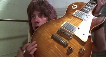 Movie still from “This Is Spinal Tap” (1984), directed by Rob Reiner – A person holding a guitar in front of their face; Close Up shot, Overhead angle