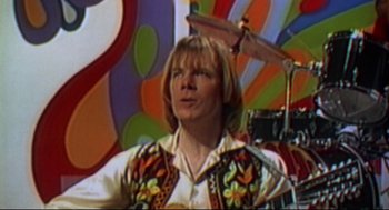 Movie still from “This Is Spinal Tap” (1984), directed by Rob Reiner – A man in a white shirt and a colorful vest; Close Up shot, Low angle