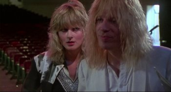 Movie still from “This Is Spinal Tap” (1984), directed by Rob Reiner – A woman and a man with blonde hair and a white shirt; Close Up shot, Over the shoulder angle