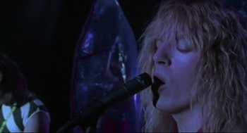 Movie still from “This Is Spinal Tap” (1984), directed by Rob Reiner – A woman with a microphone in her mouth; Close Up shot, Low angle